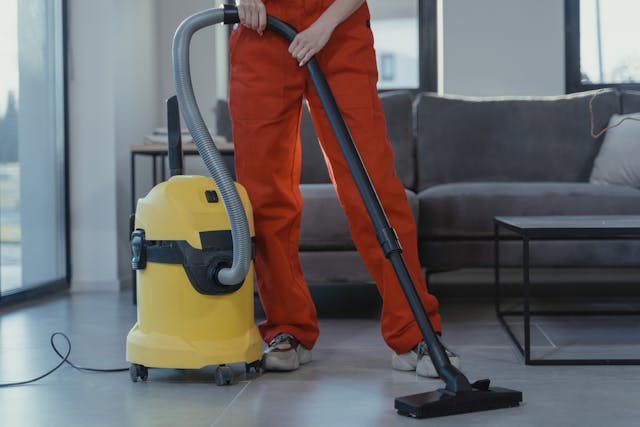someone with orange pants with a vaccuum in a living room